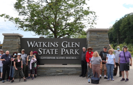 Highlight Vacations travelers standing in front of the sign to the Watkins Glen State Park in NY state.