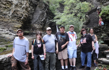 Highlight Vacations travelers standing in front of a waterfall with steps to the side that lid up the trail.