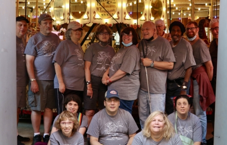 Highlight Vacations travelers posing in front of carousel from the Hershell Carousel factory museum.