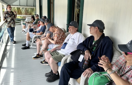 Travelers sitting on the porch of the Stranahan house listening to our guide