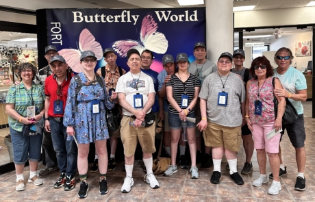 Travelers and staff at the Butterfly world in front of the sign